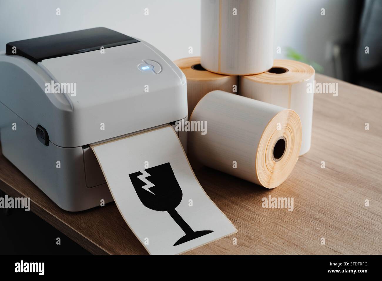 Packaging printer with rolls of labels and fragile shipping symbol for small business fulfillment. Packaging automation streamlines order processing Stock Photo