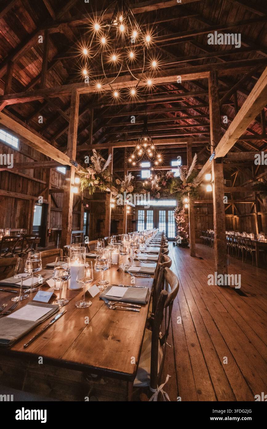 Long wooden table set for rustic barn wedding reception Stock Photo