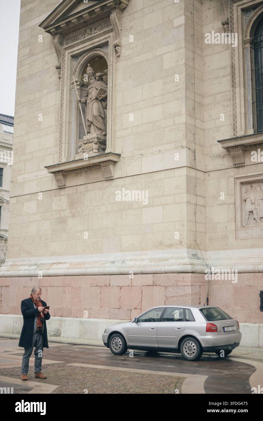 Senior man using phone in historic Budapest square Stock Photo
