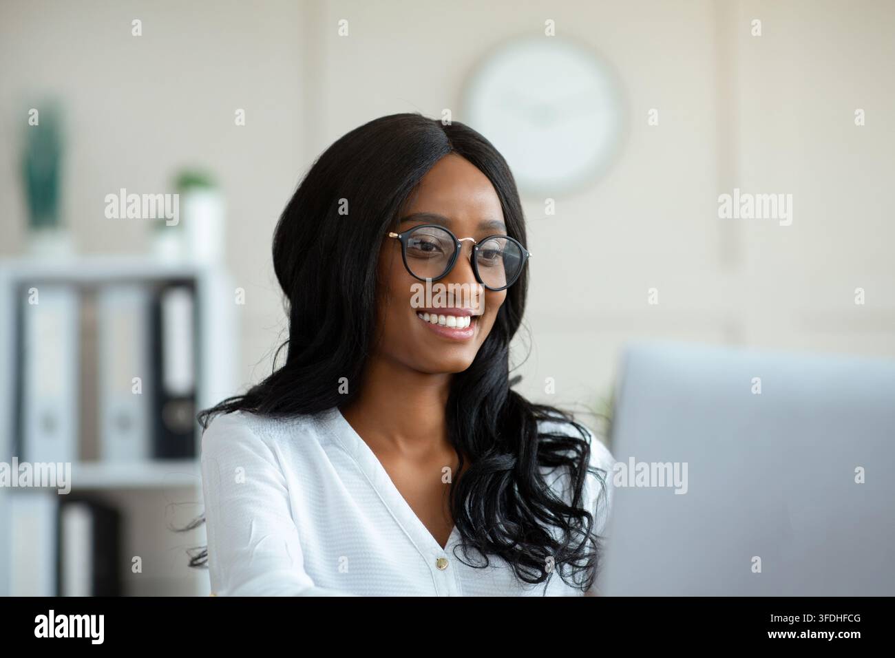 Portrait of confident black businesswoman working with laptop, checking email Stock Photo