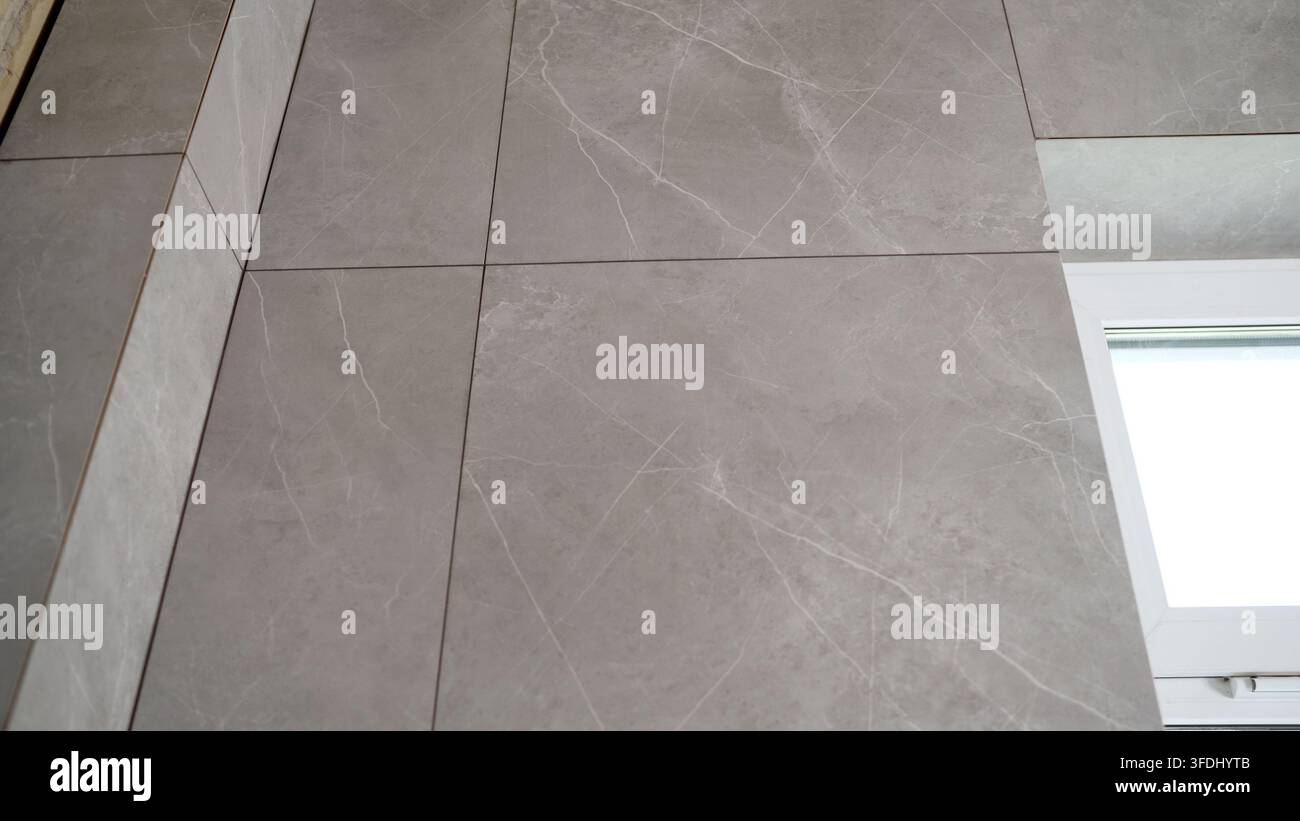 Gray marble effect tiles on wall and floor with white window frame Stock Photo