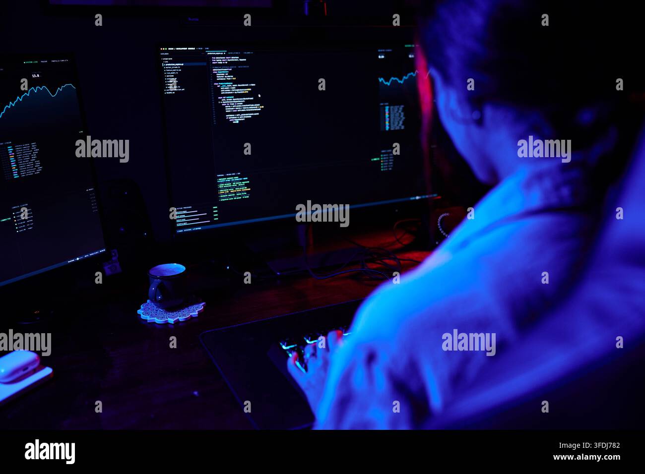Hacker or programmer writing code on multiple computer monitors, highlighting cybersecurity, technology, and data security concepts Stock Photo