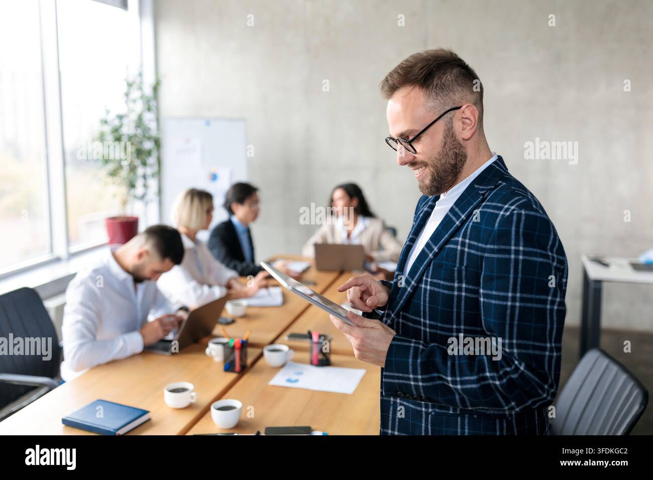 Smiling Businessman Using Digital Tablet Standing In Office Stock Photo