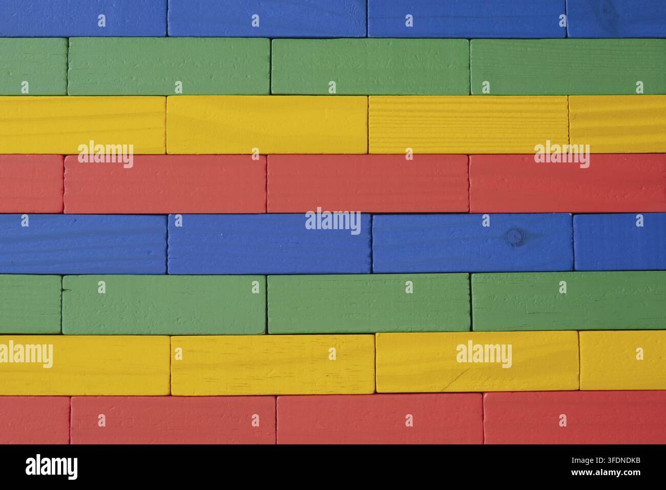 Close-up of a wall made from brightly colored wooden toy blocks (red, yellow, green, and blue) arranged in a neat geometric pattern and texture, suita Stock Photo