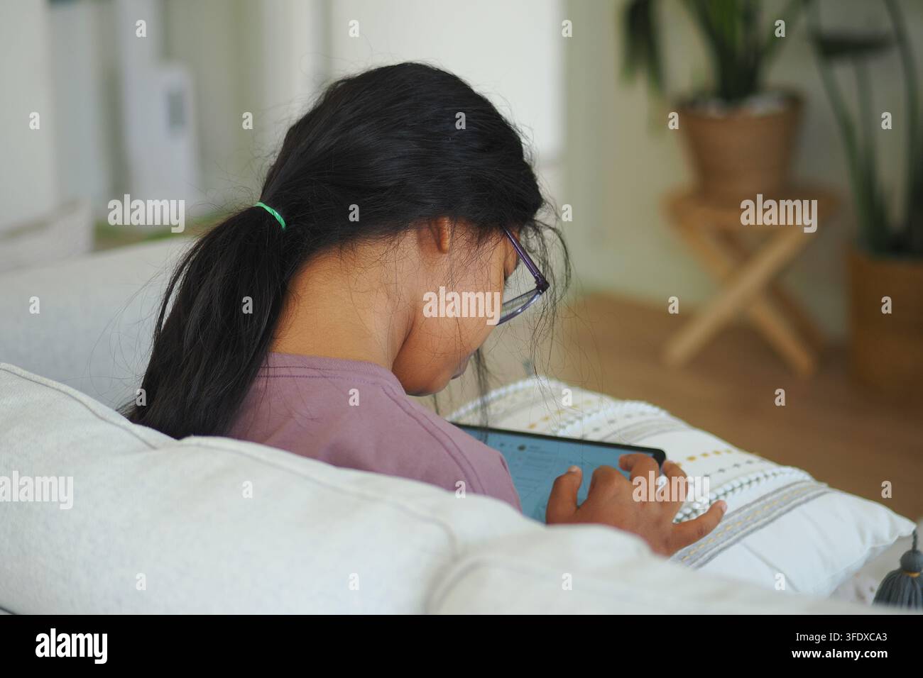 Girl using tablet while sitting on couch Stock Photo