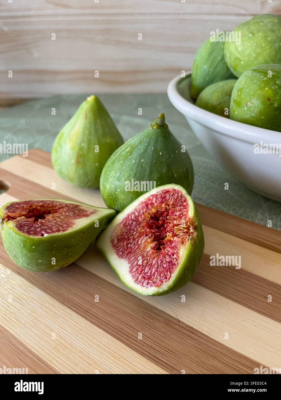 Fresh ripe figs and sliced figs arranged in bowls on a rustic wooden table. Stock Photo
