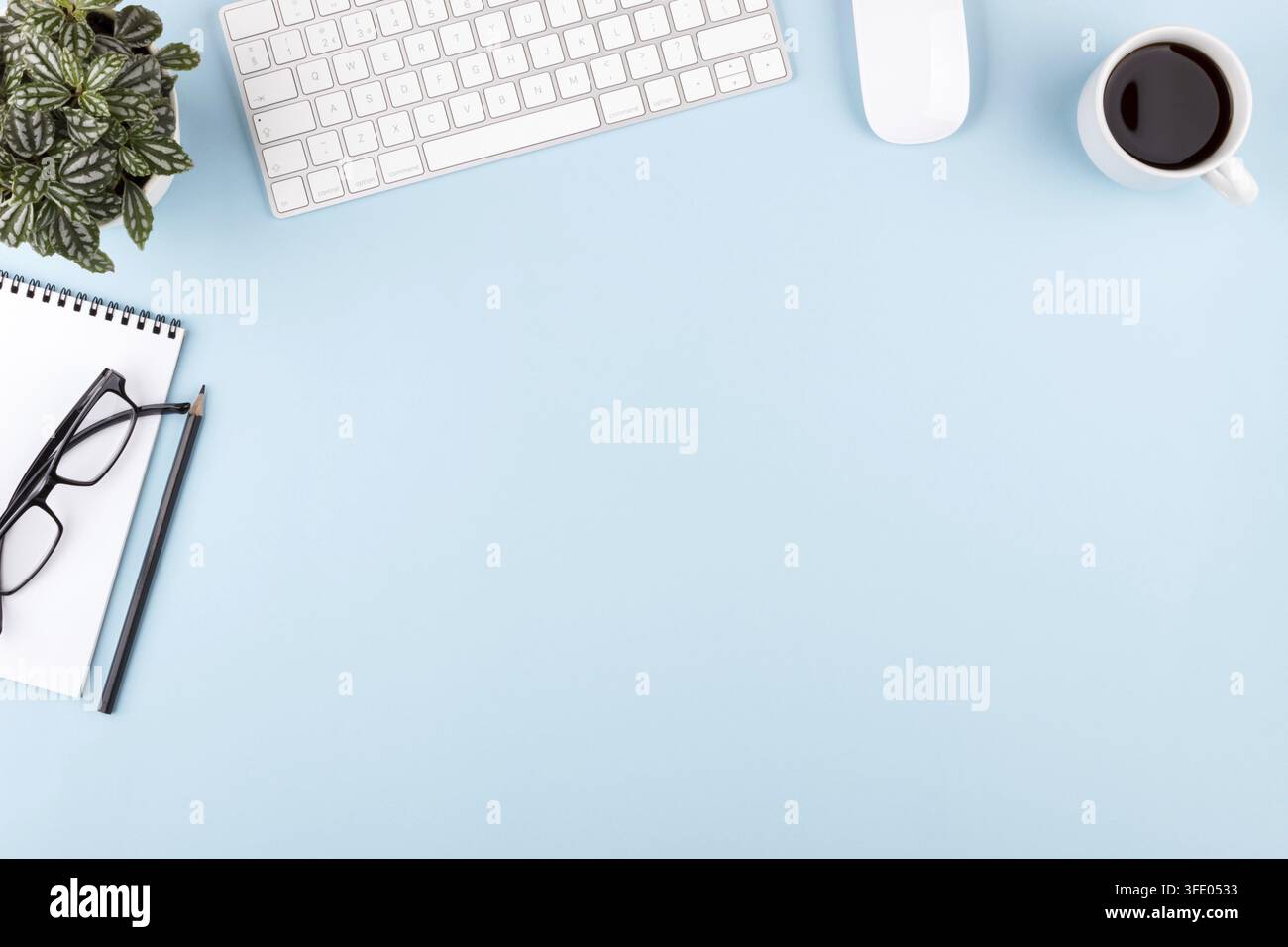 Modern office blue desk table notepad pen plant keyboard mouse glasses top view copy space Stock Photo