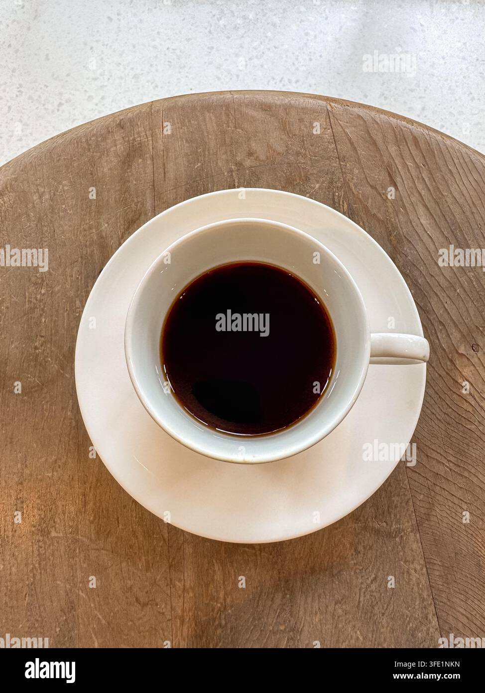 Cup of black coffee in a white ceramic cup and saucer on a rustic wooden table, photographed from above. - Smartphone Captured Stock Image