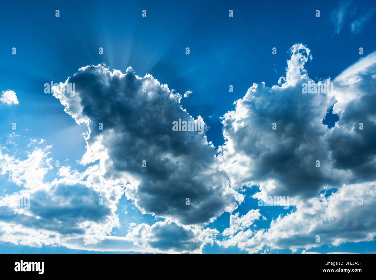 Sun rays breaking through clouds in blue sky Stock Photo