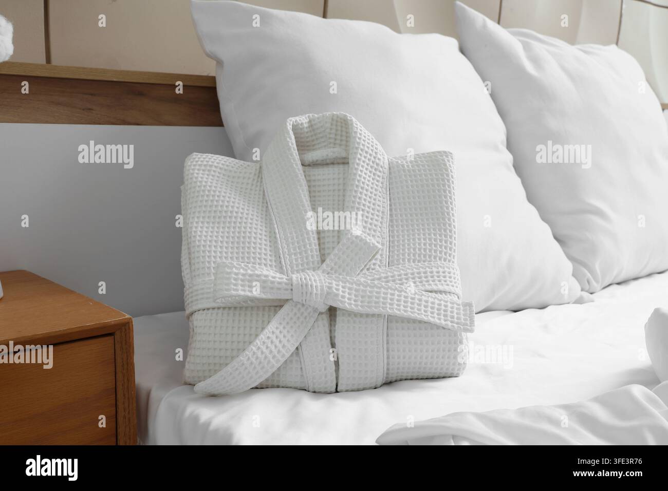 Folded waffle bathrobe on bed in room Stock Photo
