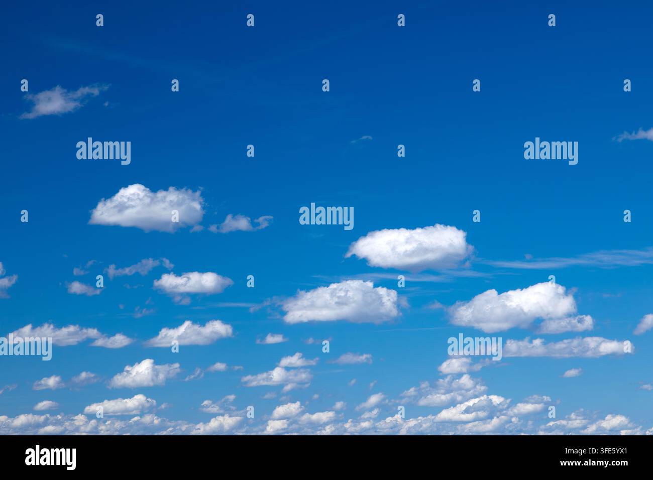Sky background with fluffy white clouds on a bright blue sky Stock Photo