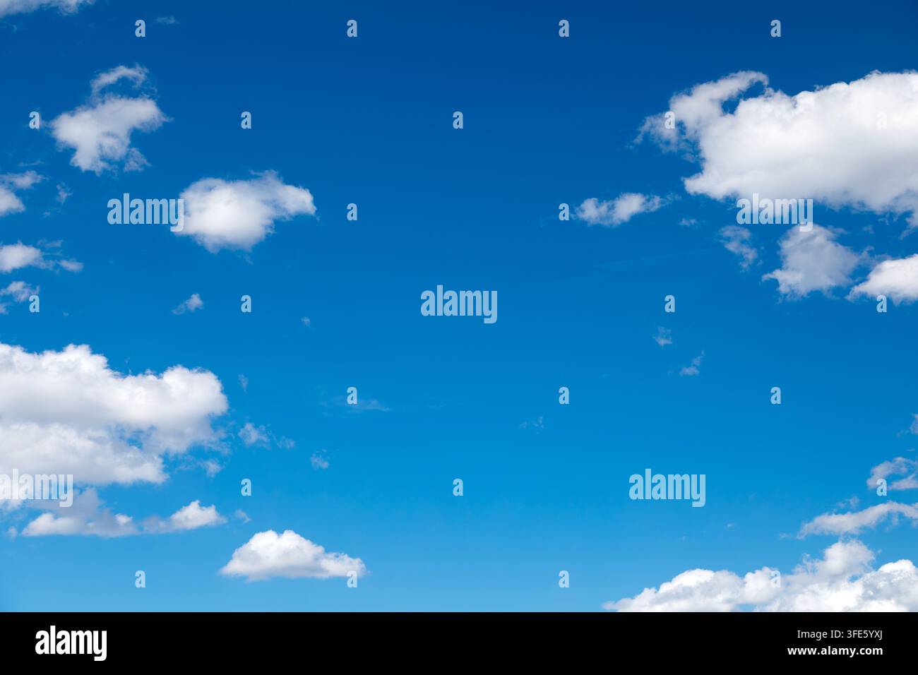 Sky background with fluffy white clouds on a bright blue sky Stock Photo