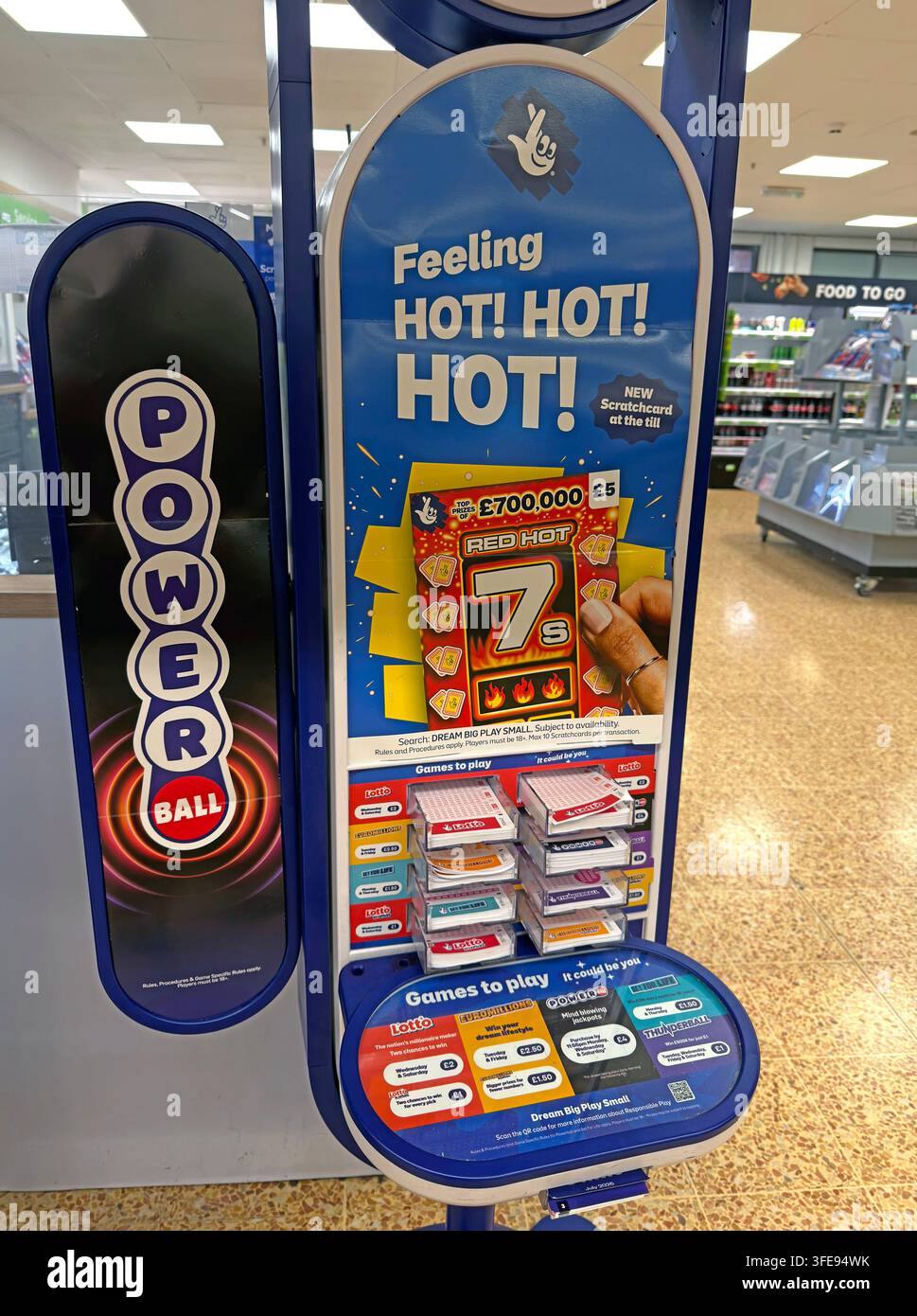 UK National Lottery retail display promoting Powerball and the £5 Red Hot 7s scratchcard with a £700,000 top prize. Stock Photo