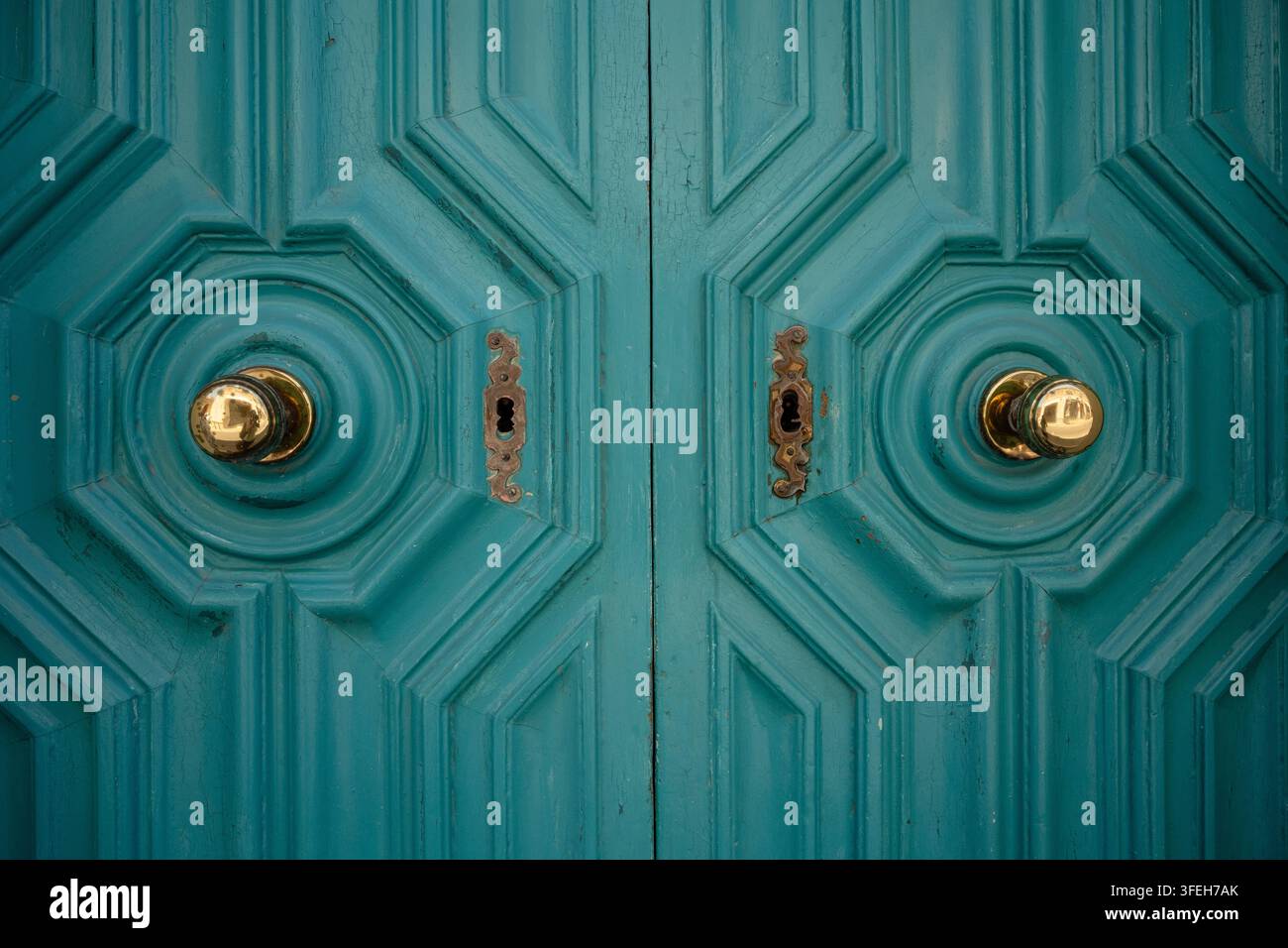 Symmetrical vintage teal doors with brass knobs Stock Photo