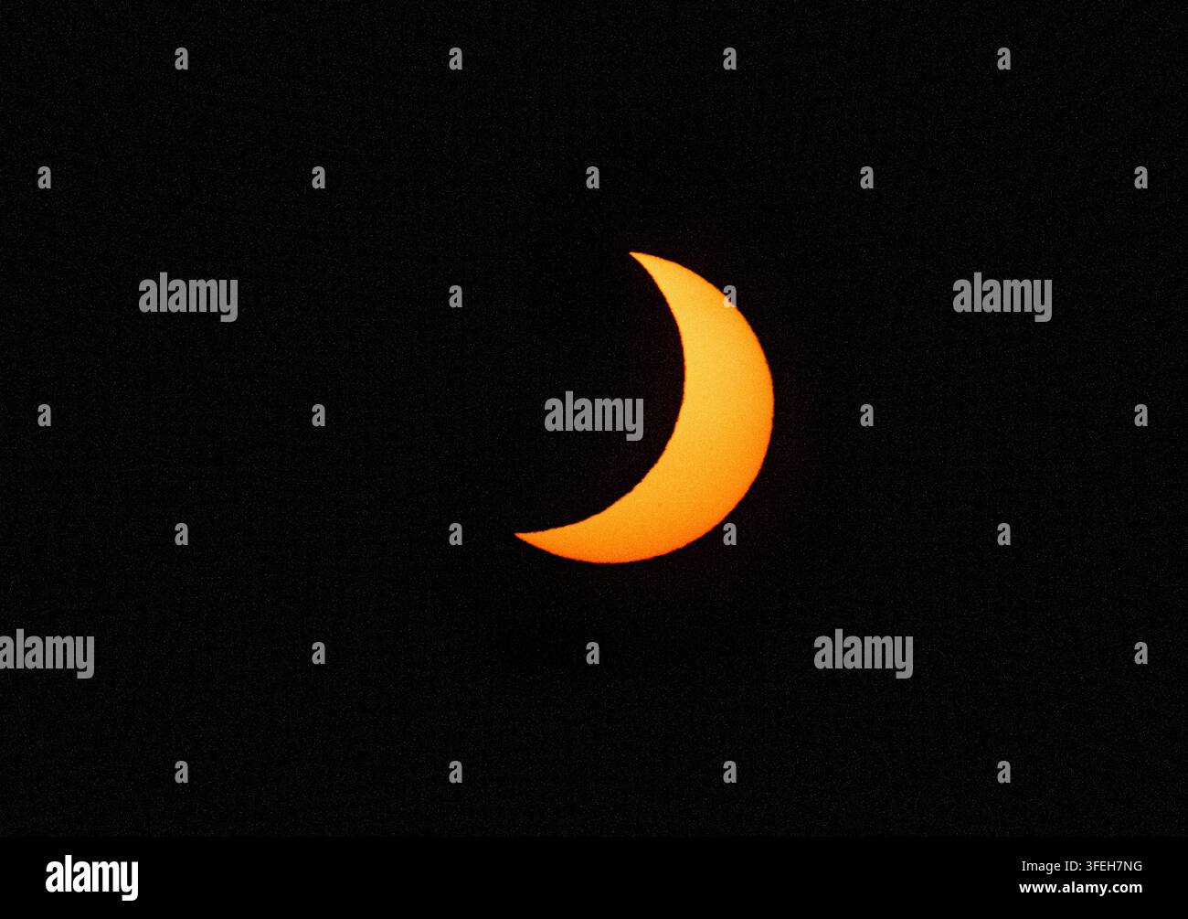 Orange crescent sun during a partial solar eclipse Stock Photo
