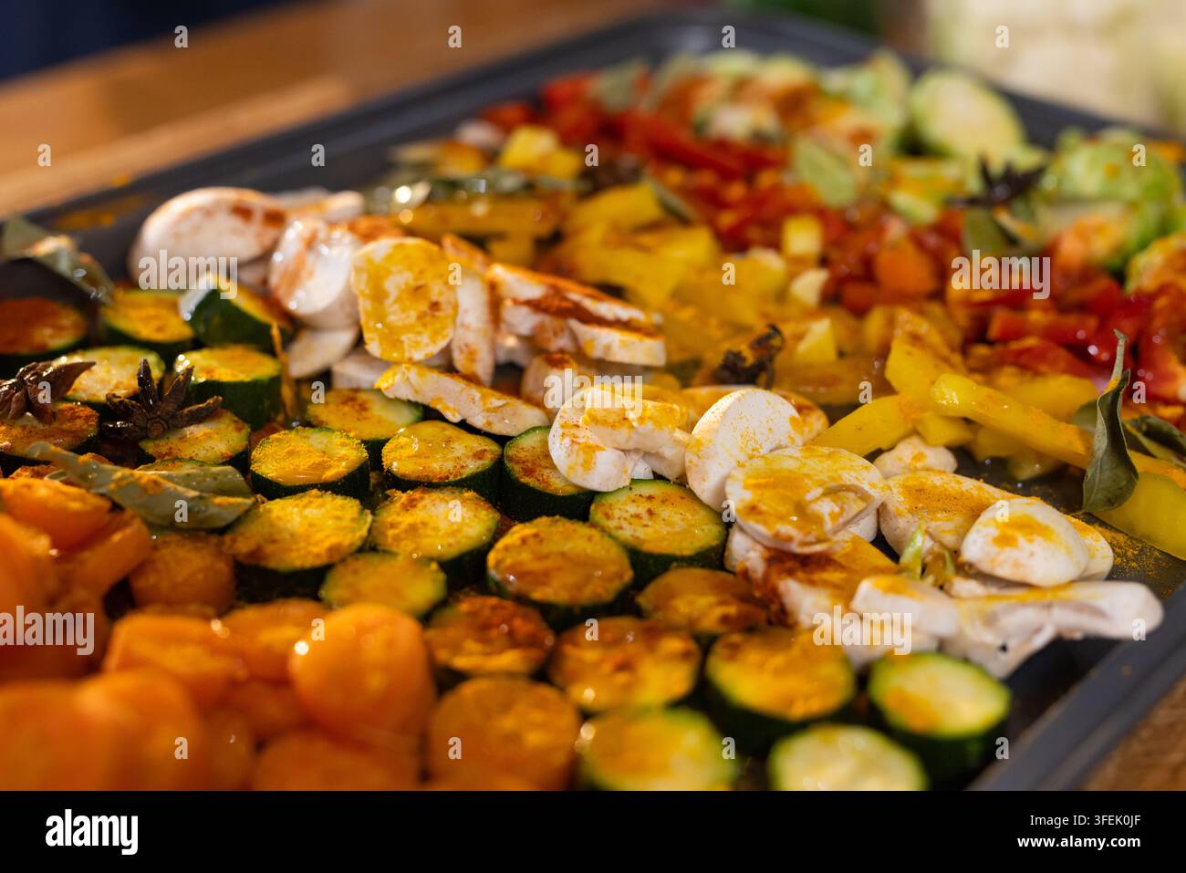 Roasted vegetables are glistening on baking sheet in kitchen, showing zucchini, mushrooms, peppers Stock Photo
