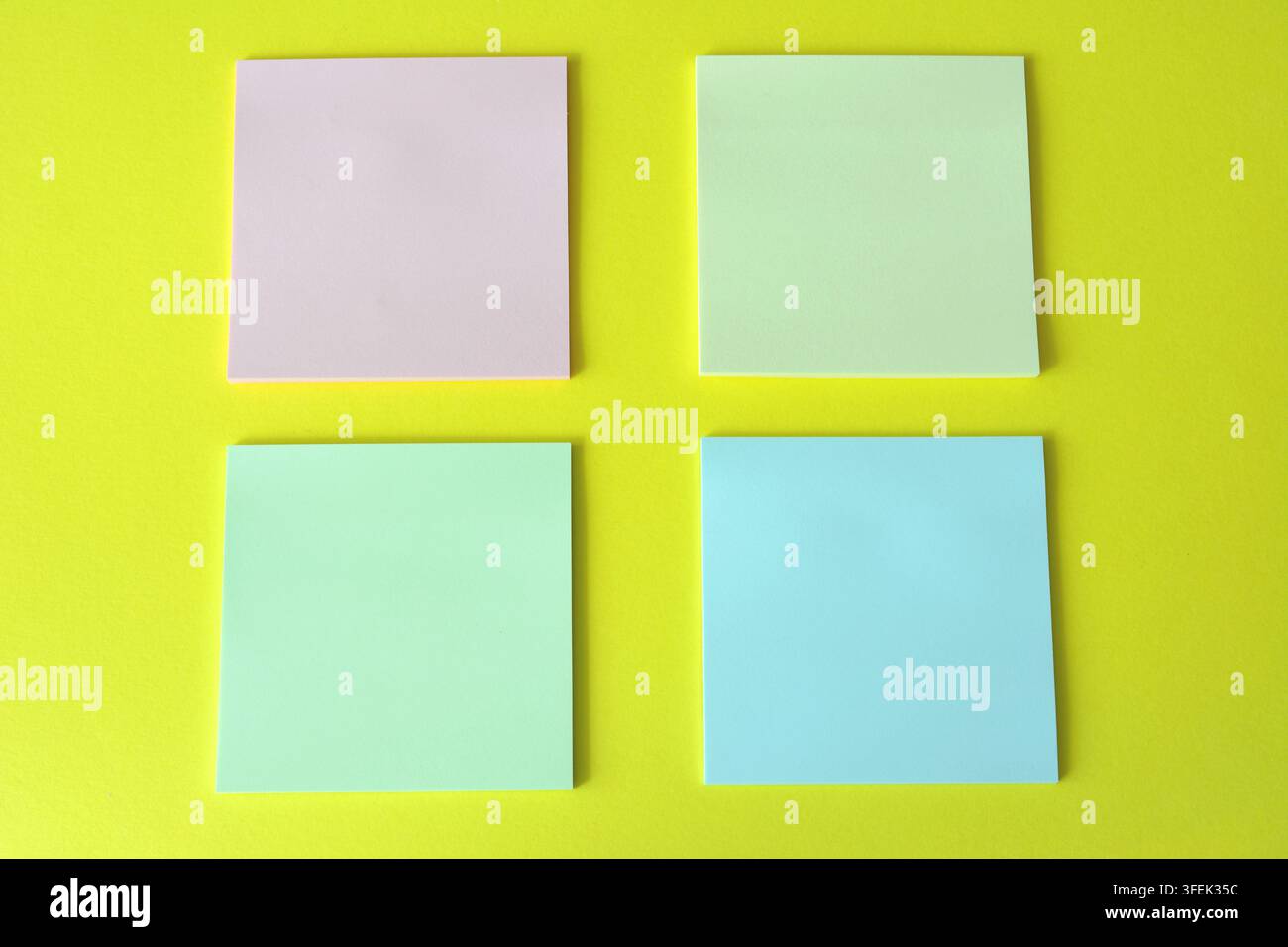 Four Square Sticky Notes on Yellow Background, high angle view, copy space Stock Photo