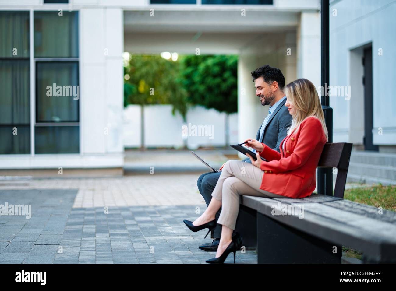 Business professionals collaborating outdoors using digital tablet and laptop Stock Photo