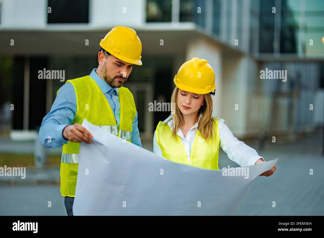 Engineers discussing blueprints planning construction project on site Stock Photo