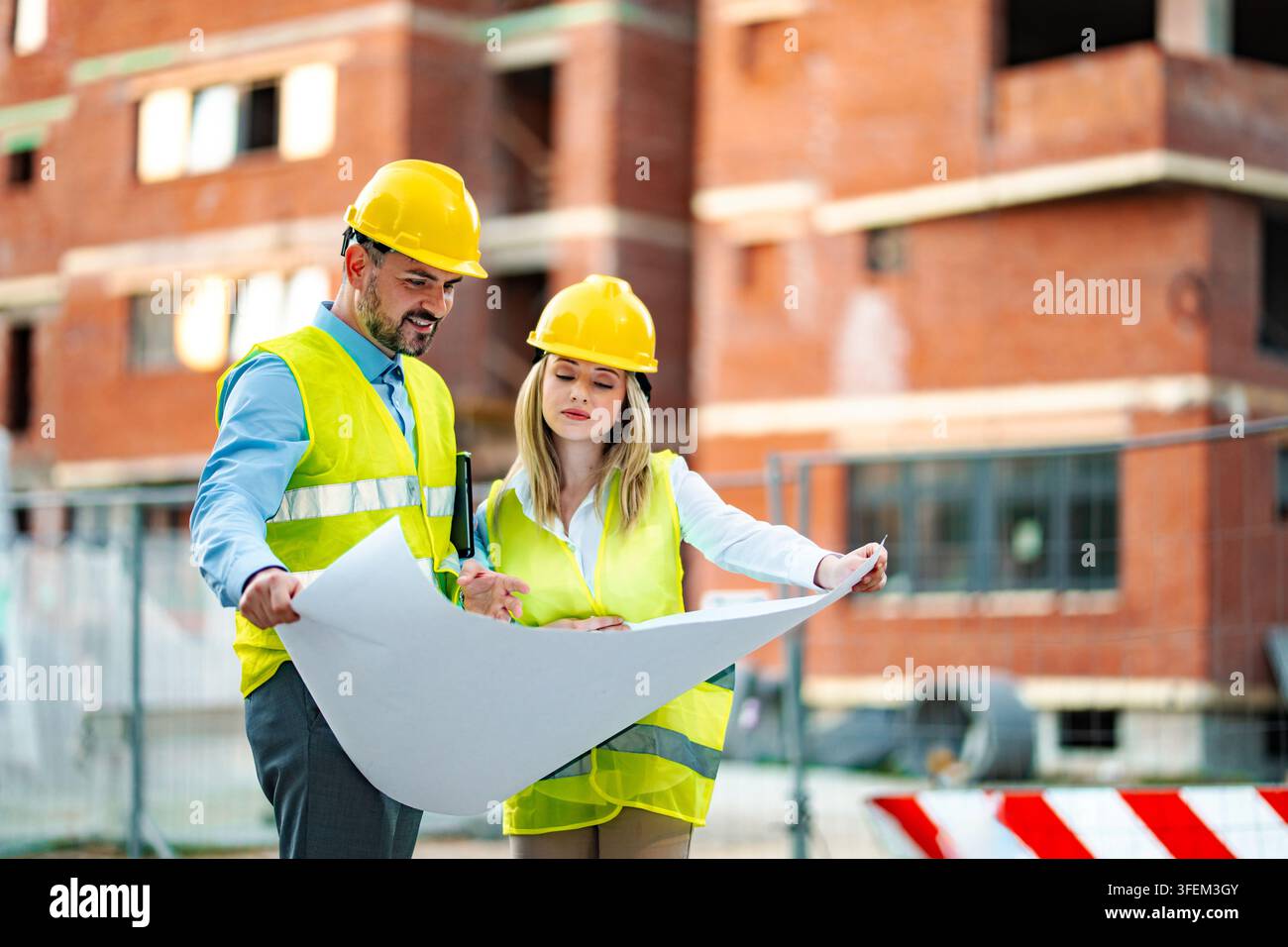 Engineers reviewing blueprint at construction site Stock Photo