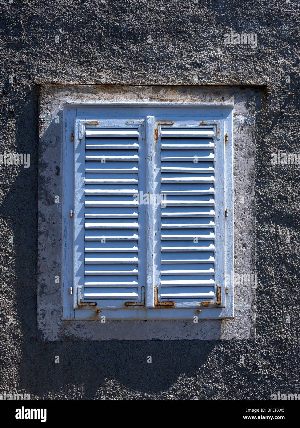 Old pale blue louvre vent on small window in stone wall for use as a background Stock Photo