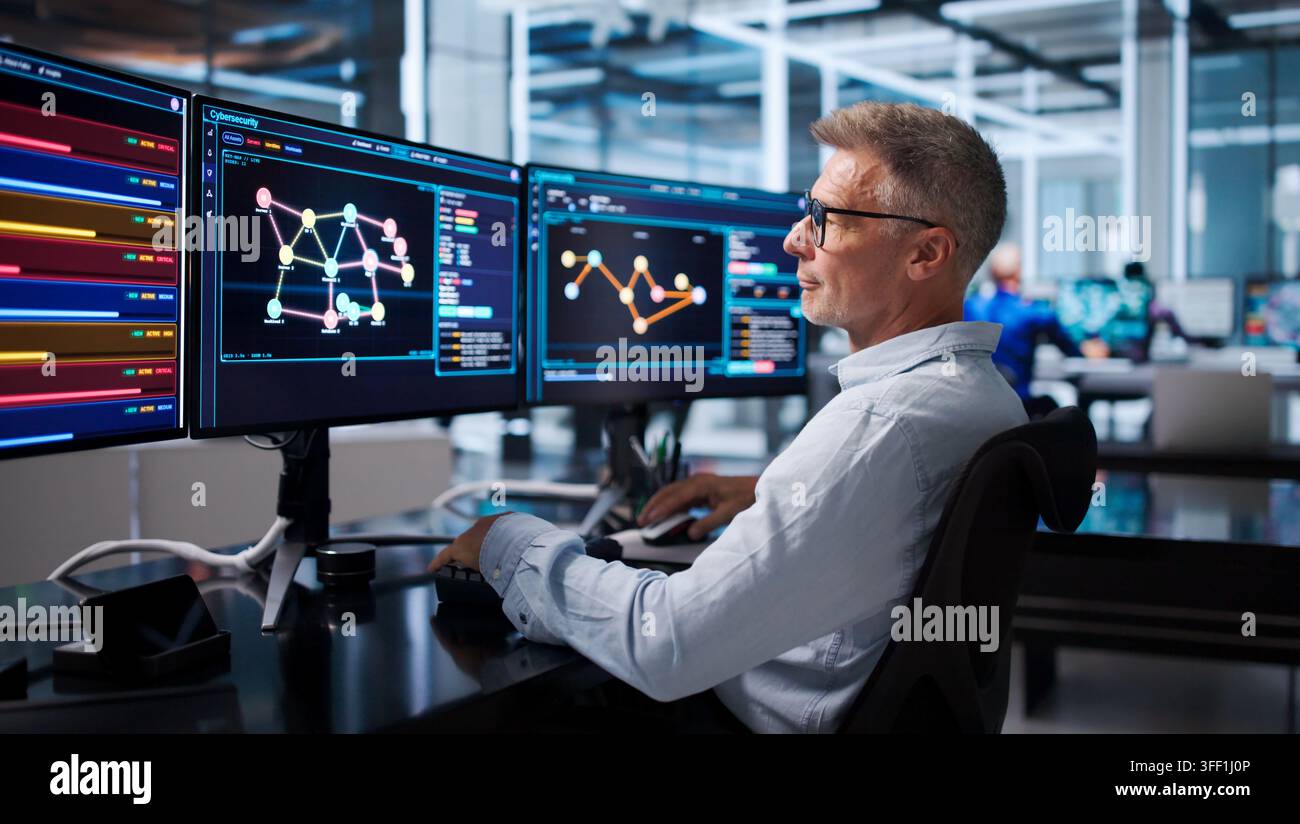Senior Software Developer Pointing At Screen While Debugging Code Remotely. Stock Photo