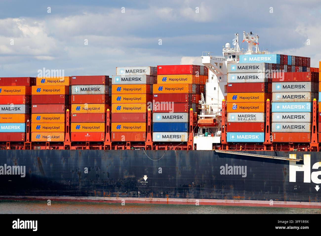 Maersk shipping containers, and Hapag-Lloyd shipping containers stacked onboard a container ship operated by Hapag-Lloyd, a German shipping company Stock Photo