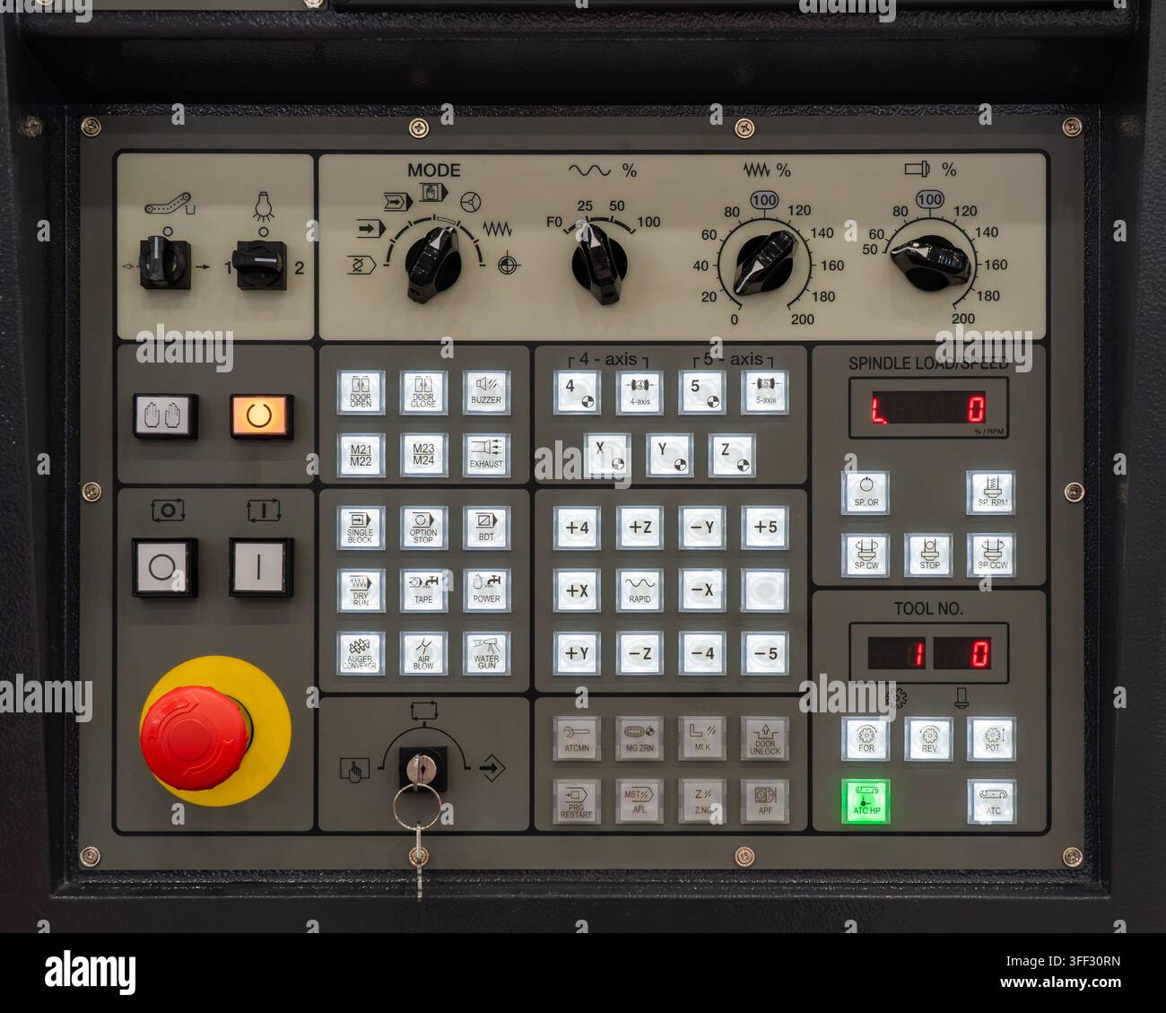 Industrial CNC machine control panel keyboard with emergency stop button, spindle controls, digital displays and illuminated function keys Stock Photo