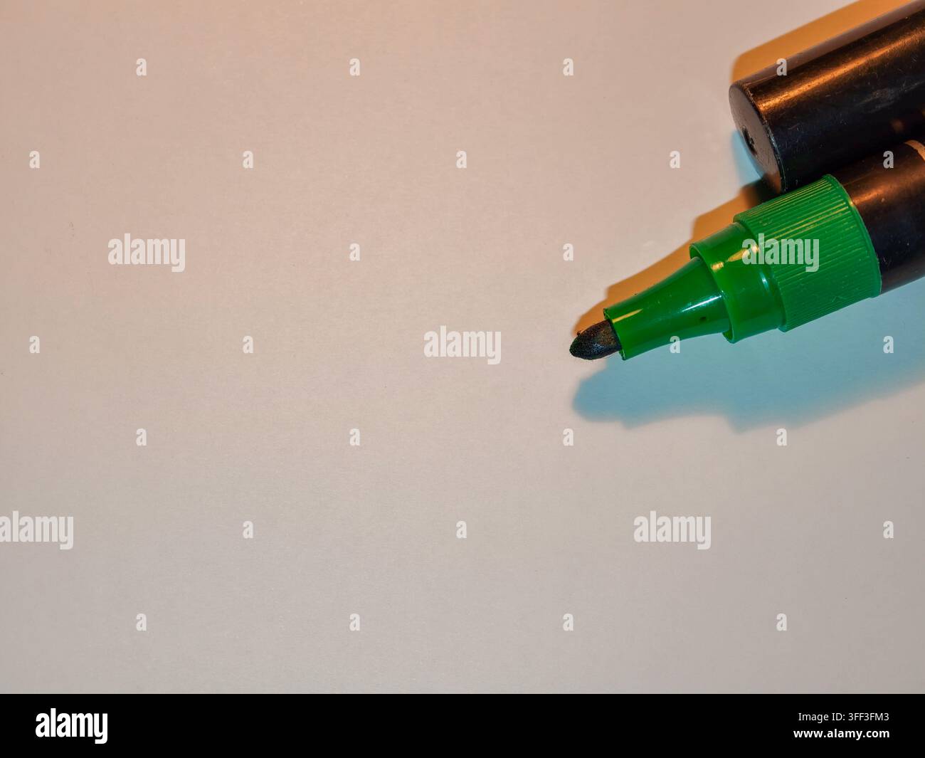 Green marker pen with its cap resting on top, positioned in the upper right corner, showing the felt tip on a checkered transparent background with am Stock Photo