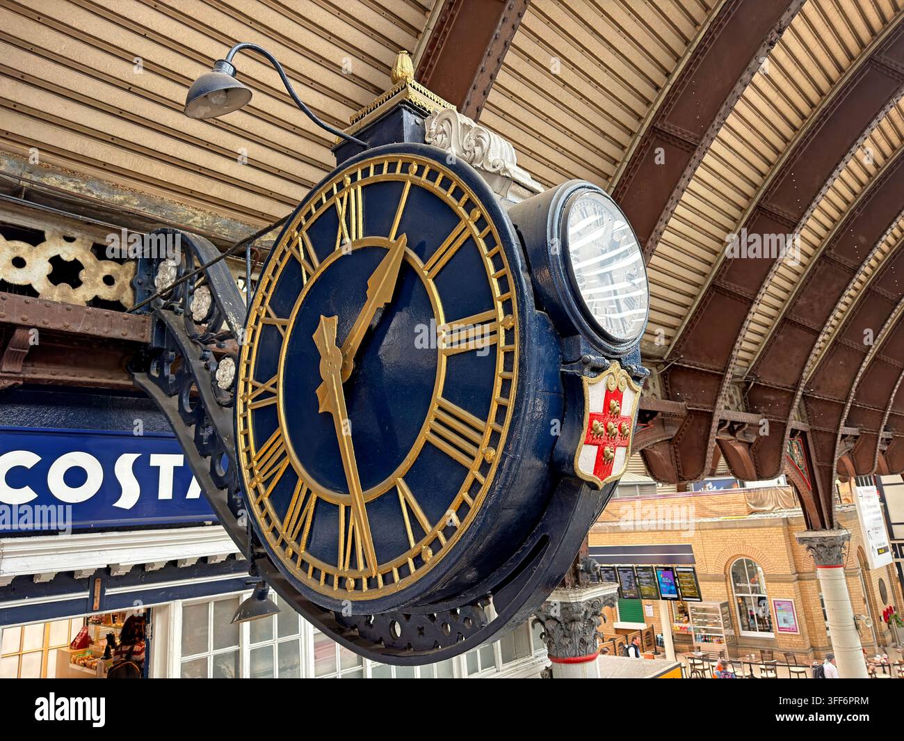 Historic Victorian projecting clock beneath the train-shed roof at York railway station, decorated with the City of York coat of arms Stock Photo