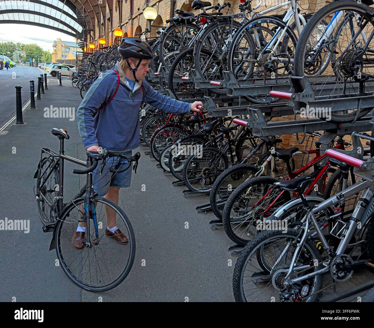 Cyclist collects a bike from crowded racks at York station, showing integrated rail travel, cycle parking and sustainable commuting. Stock Photo
