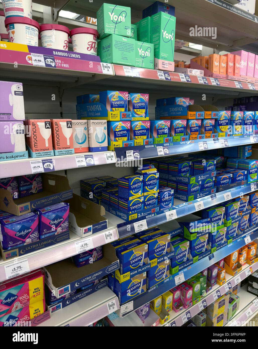 Women's sanitary products in a UK supermarket, including tampons, pads and menstrual cups on a crowded personal-care shelf. Stock Photo