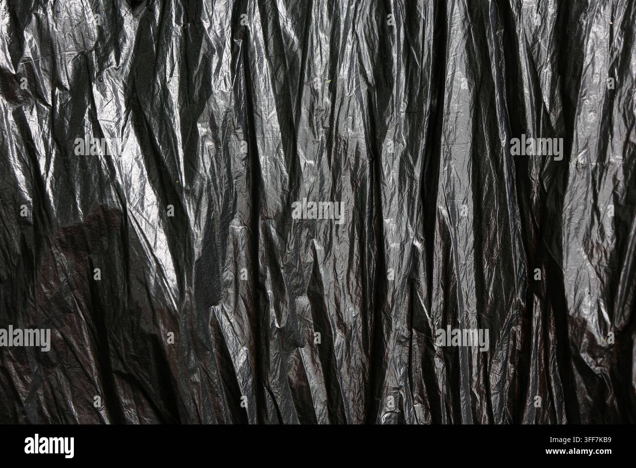A black plastic texture wrinkle pattern crumpled vertical dark background abstract crumpled black plastic texture with vertical wrinkle pattern creati Stock Photo