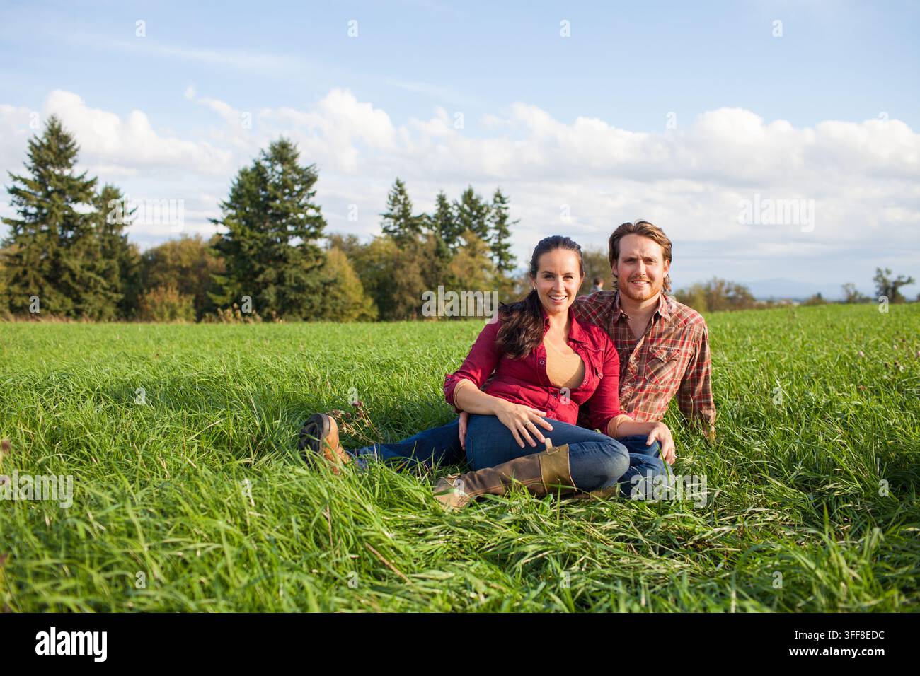 Smiling couple sitting together in a grassy field Stock Photo