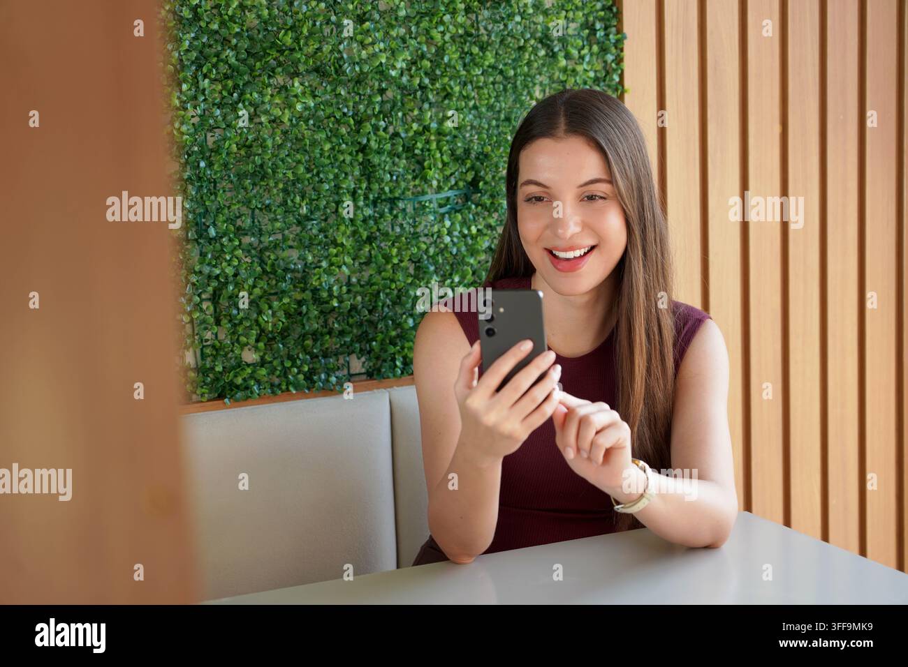 Smiling Brazilian business woman using banking app on mobile phone indoor Stock Photo
