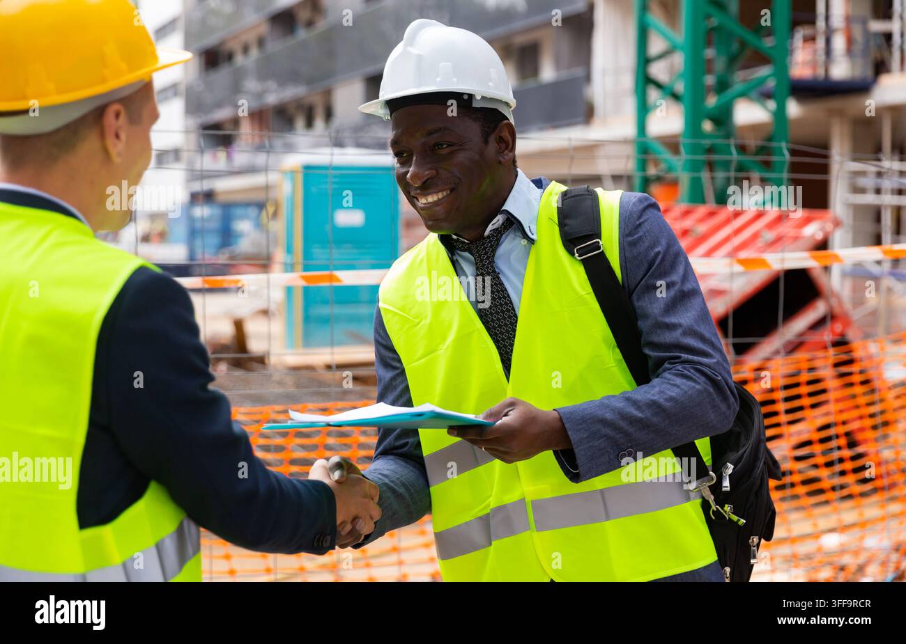Engineers shaking hands on construction site Stock Photo