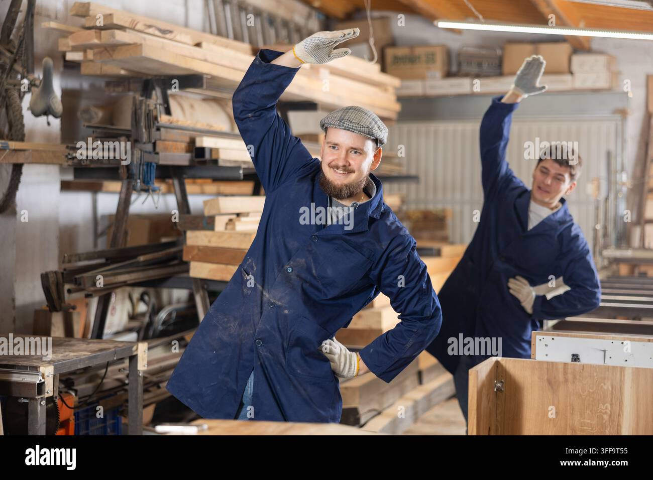 Two funny sawmill workers perform various funny moves Stock Photo