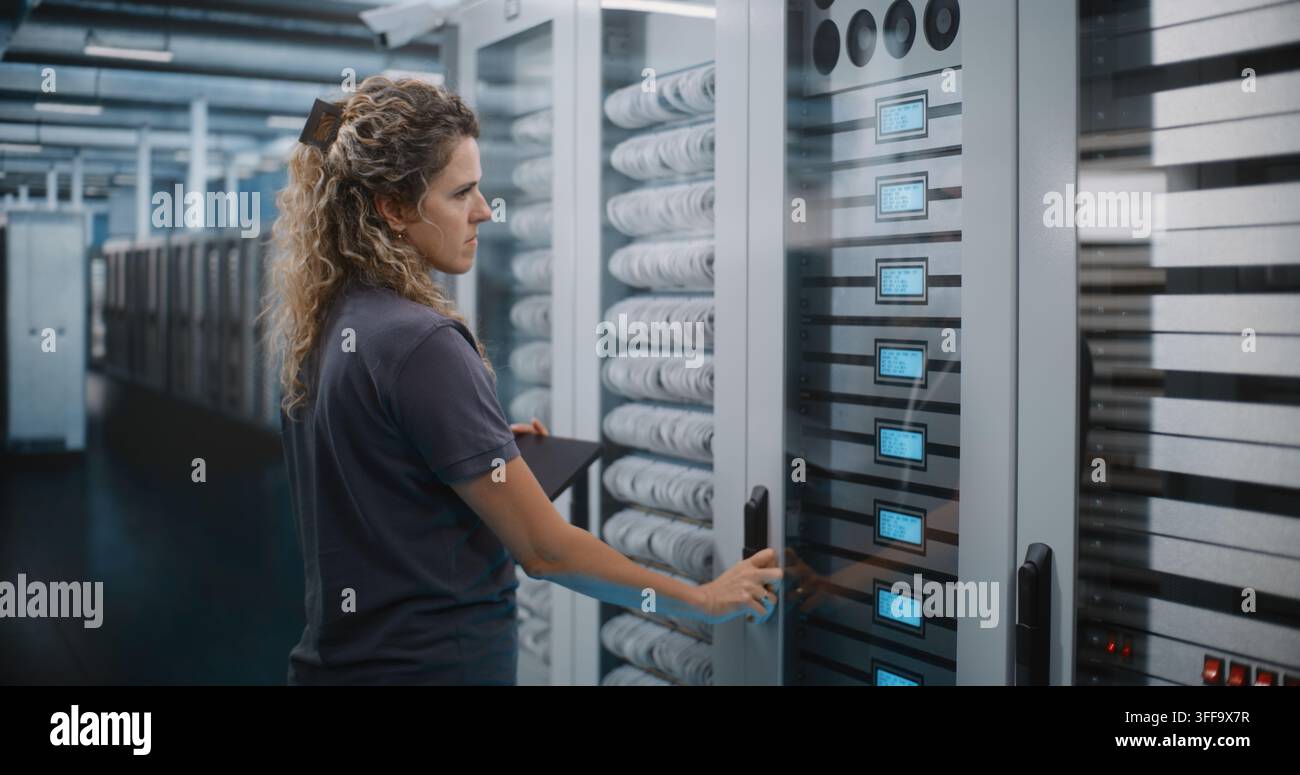 Female Network Administrator Types on Laptop while Analyzing Server Rack Hardware Modules and Cabling. Cybersecurity Management and Cloud Storage Audit Safeguard Critical Enterprise databases. Stock Photo