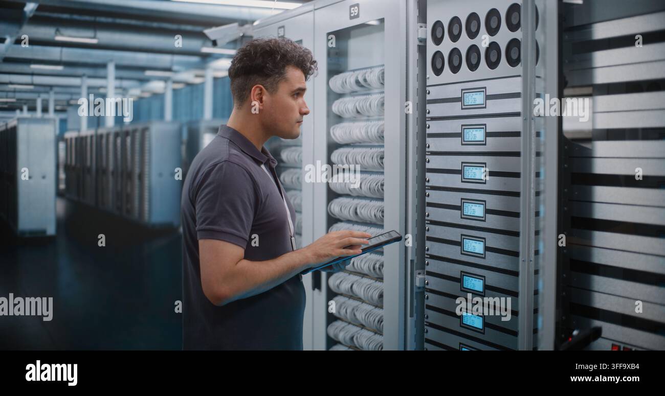 IT Engineer Holds Digital Tablet while Touching and Inspecting Server Rack Modules in Modern Data Center. Routine Hardware Maintenance, Physical Checks Ensure High Availability Server Infrastructure. Stock Photo
