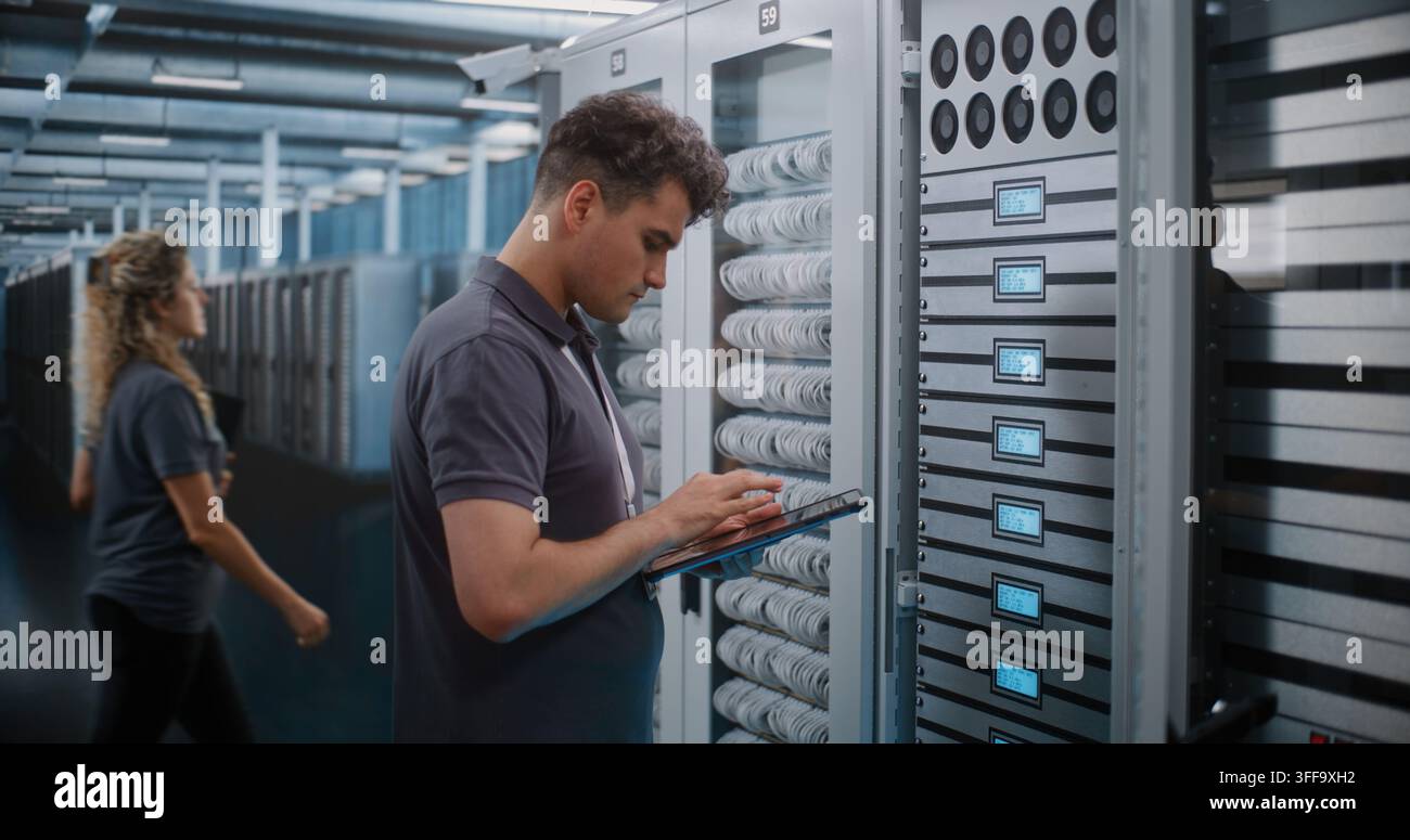 IT Engineer Holds Digital Tablet while Touching and Inspecting Server Rack Modules in Modern Data Center. Routine Hardware Maintenance, Physical Checks Ensure High Availability Server Infrastructure. Stock Photo