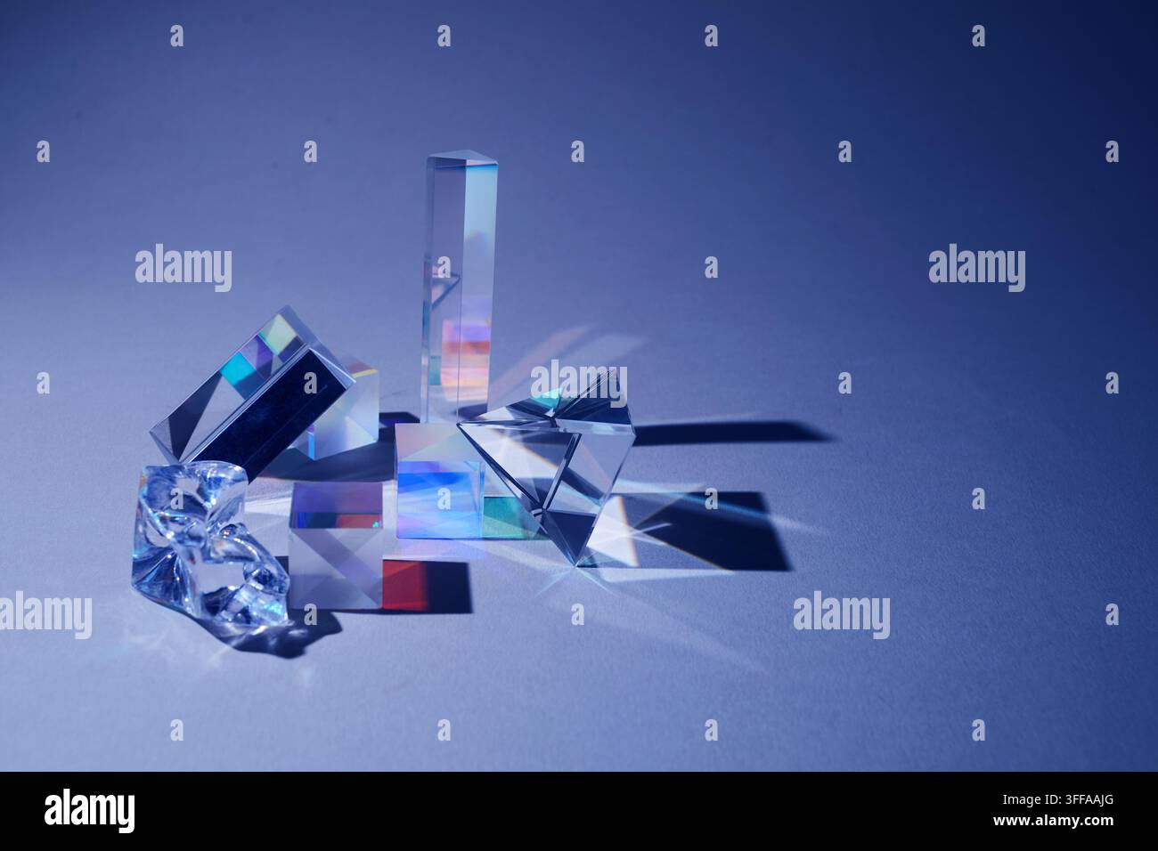 Glass prisms refracting light creating spectrum on blue background Stock Photo
