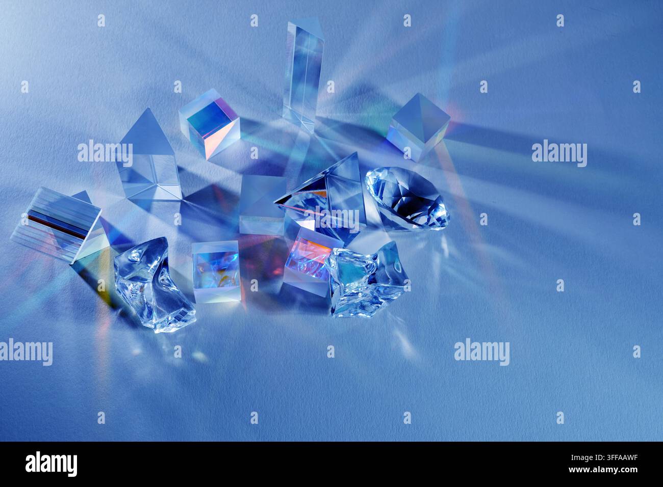 Prisms refracting light creating colorful spectrum on blue Stock Photo