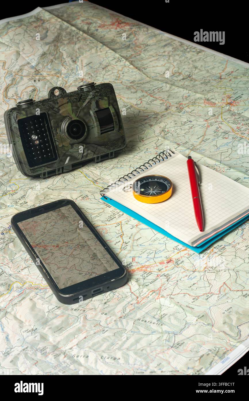 Wilderness planning with map, compass, smartphone, trail camera Stock Photo
