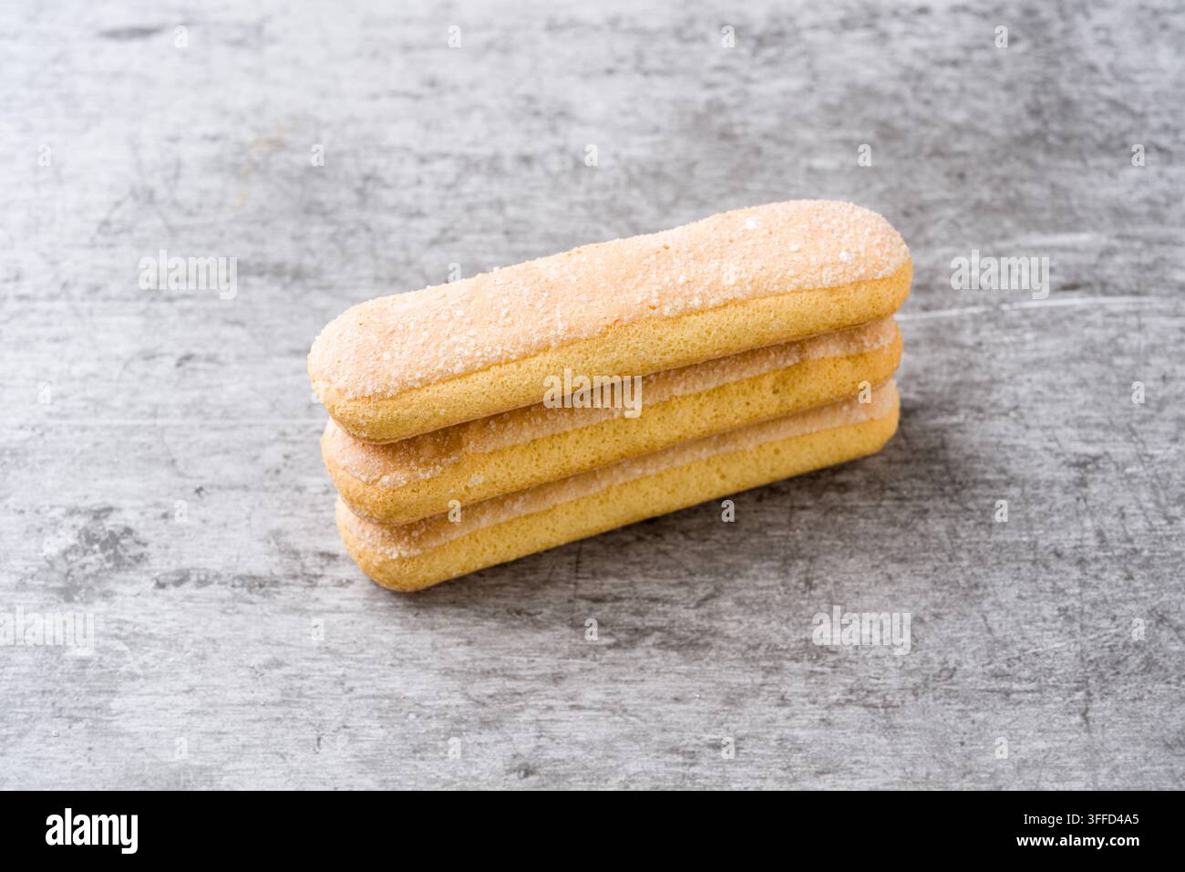 Stacked Savoiardi biscuits on gray surface with generous copy space Stock Photo