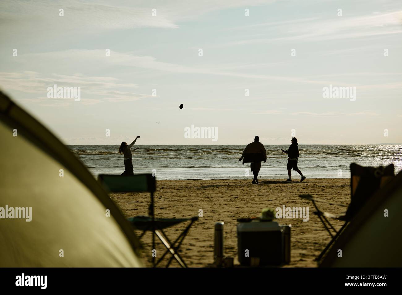 Friends Playing with Ball on Beach during Camping Trip Stock Photo