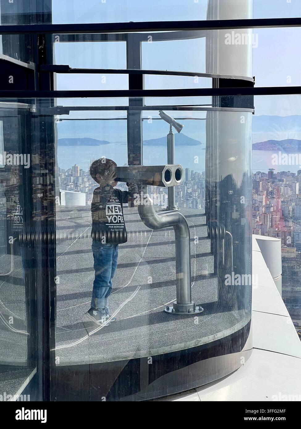 A boy looking through coin-operated binoculars on an observation deck with a panoramic view. Stock Photo