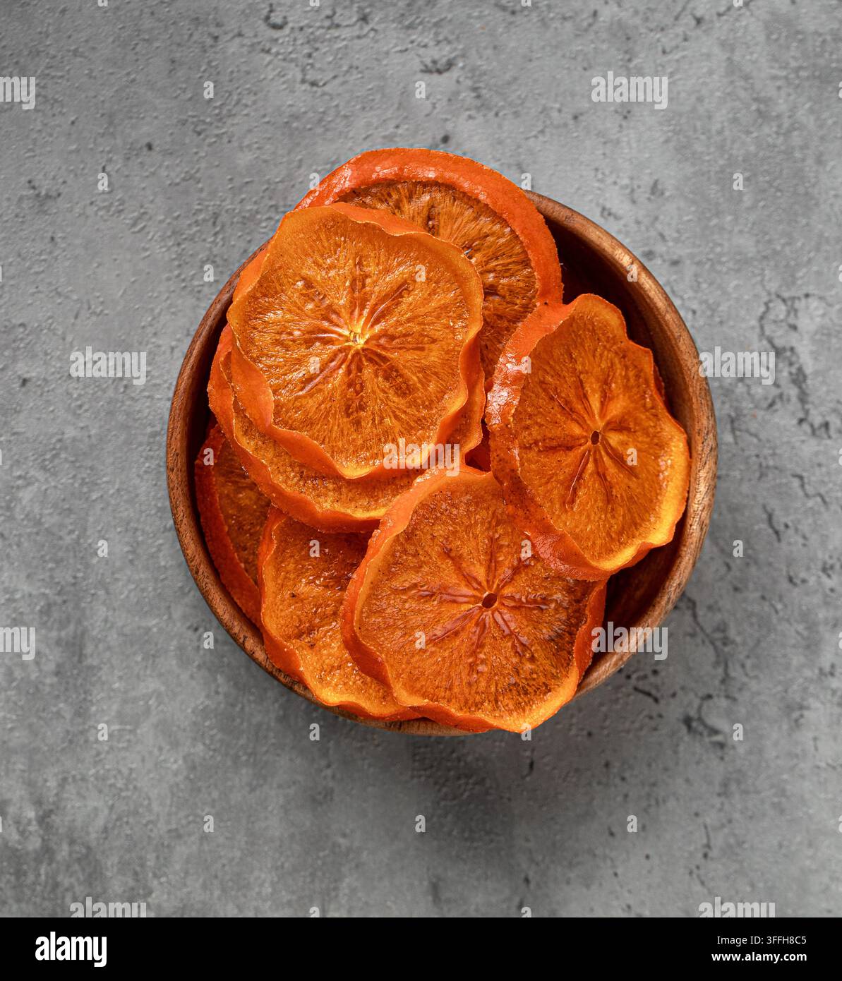 Dried orange slices in wooden bowl on stone Stock Photo