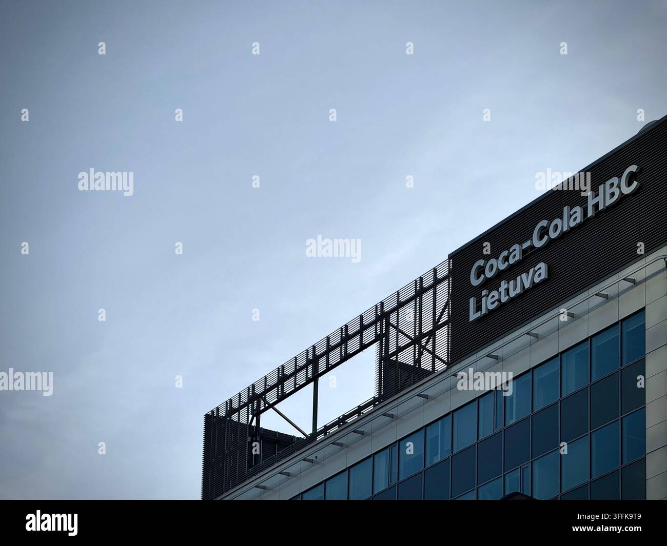 Low-angle photo of the "Coca-Cola HBC Lietuva" corporate logo on a modern office facade in Vilnius, Lithuania. - Smartphone Captured Stock Image
