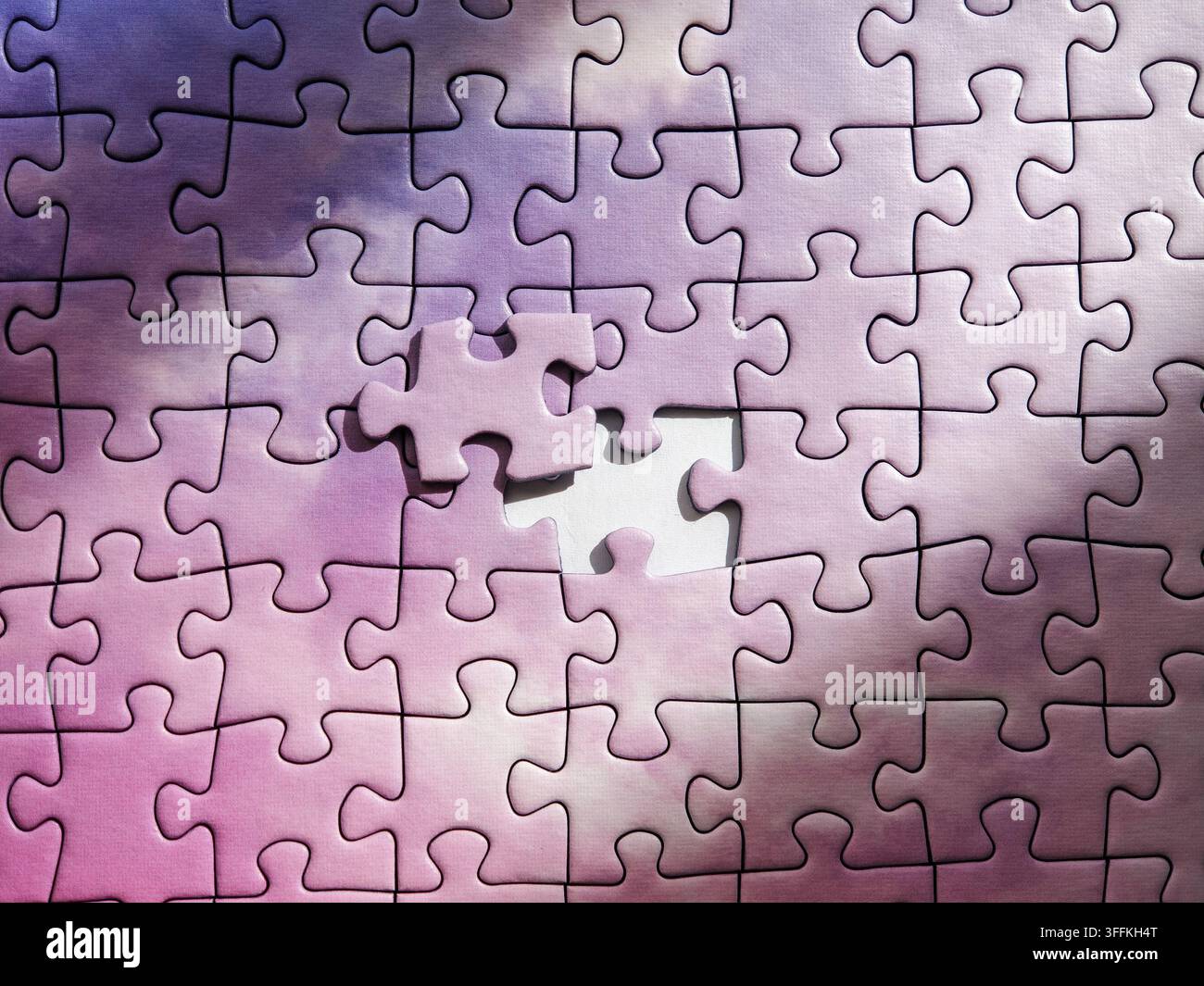 Purple jigsaw puzzle background with single missing element being inserted Stock Photo