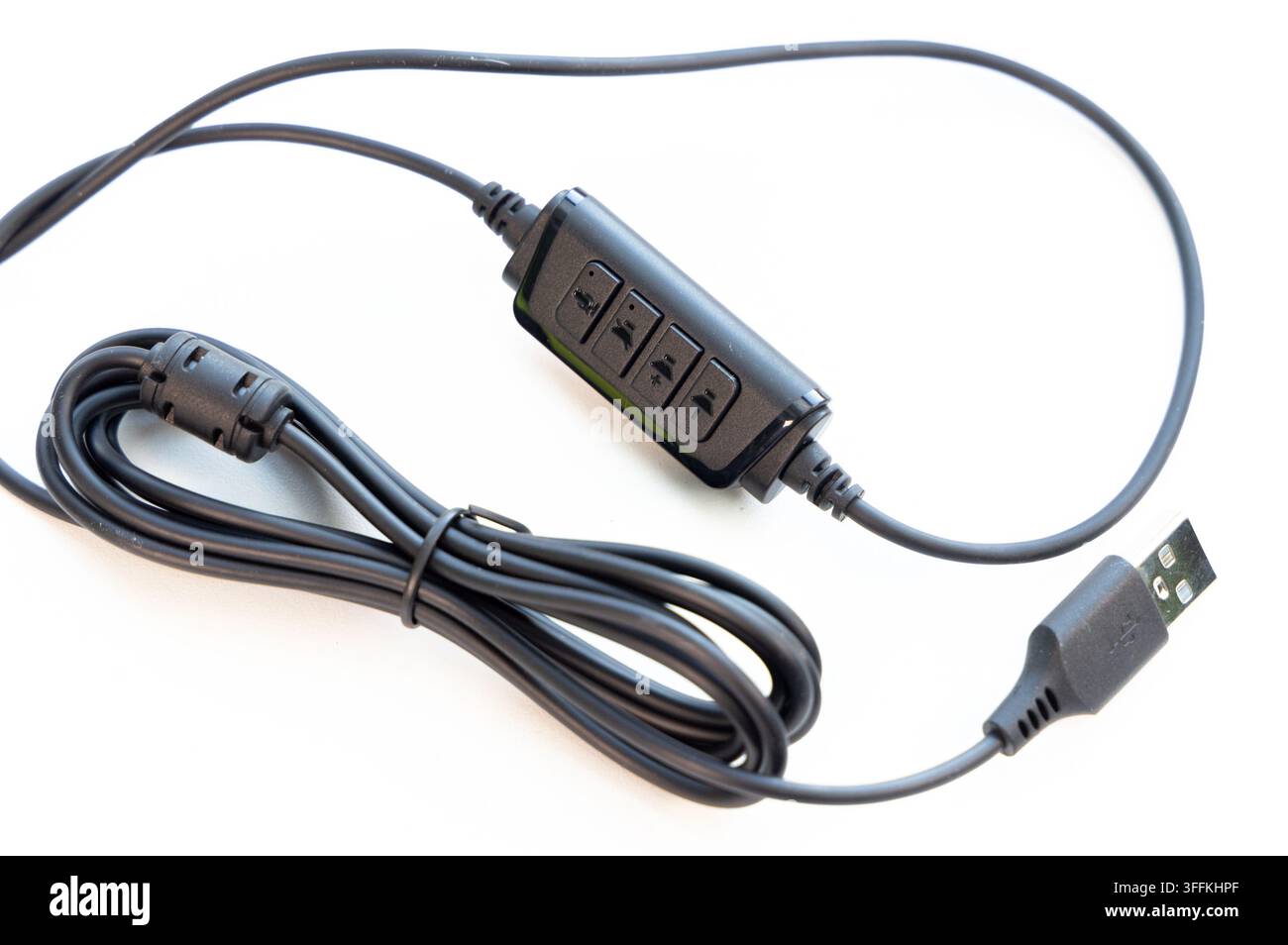 A black USB audio cable with inline controls rests on a white surface Stock Photo